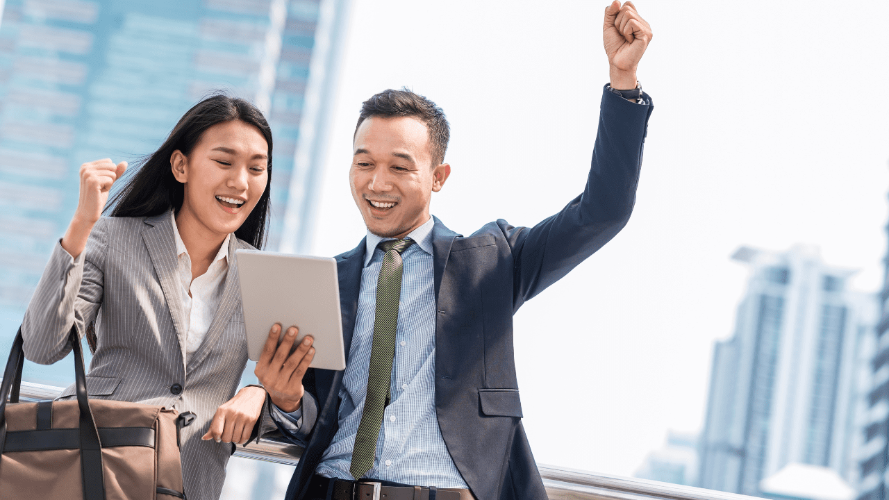 A man and woman celebrating their 186 visa by looking at a piece of paper